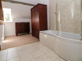 A bathroom with a bathtub and a dark wood wardrobe and chest of drawers at New Hall in Chirk