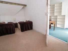 A bedroom with two single beds covered with dark blankets and rolled towels on them at New Hall in Chirk