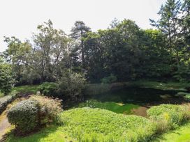 A garden area with a pond surrounded by bushes and trees at New Hall in Chirk