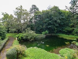 A garden with a pond surrounded by trees and shrubs at New Hall in Chirk