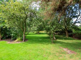 A grassy garden area with several trees and shrubs at New Hall in Chirk