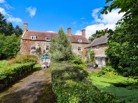 An outdoor garden area with a stone house patio furniture and a small pond at New Hall in Chirk
