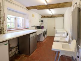 A laundry room with washing machines dishwasher high chairs and an ironing board at New Hall in Chirk