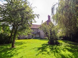 A stone house with multiple windows surrounded by grass and trees at New Hall in Chirk