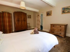 A bedroom with a white bedspread three folded towels on the bed a wooden wardrobe a wooden chest of drawers a wooden chair and framed pictures on the walls at New Hall in Chirk