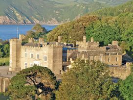 A castle surrounded by trees and water at Watermouth Castle, Harbour Apartment Berrynarbor near Ilfracombe