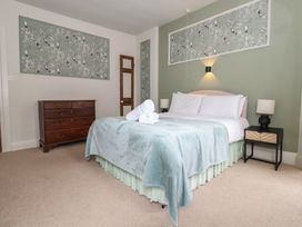 A bedroom with a bed, dresser, and wall art at Watermouth Castle, Penn-Curzon Apartment Berrynarbor near Ilfracombe