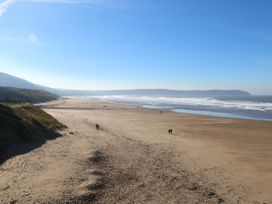 A beach with people walking and waves at Watermouth Castle, Rhododendron Apartment Berrynarbor near Ilfracombe