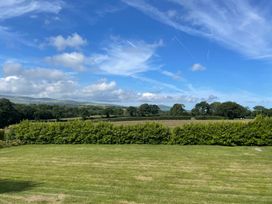 A view of green grass and trees under a blue sky at Bryn Tawel Eglwyswrw