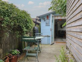 An outdoor area with a table and chairs next to a shed at The Artist's Cabin By The Sea Herne Bay