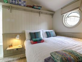 A bedroom with a bed, pillows, and a round window at The Artist's Cabin By The Sea in Herne Bay
