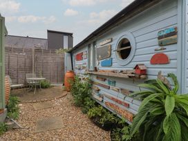 A garden with a table and chairs near a decorated shed at The Artist's Cabin By The Sea in Herne Bay