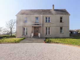 The front of a two-story house with a stone pathway steps leading to a wooden door at Hen Ficerdy Abererch near Pwllheli