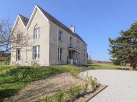 A two-story house with multiple windows surrounded by grass and a gravel driveway at Hen Ficerdy Abererch near Pwllheli