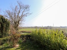 A garden with bushes and trees overlooking green fields at Hen Ficerdy in Abererch near Pwllheli