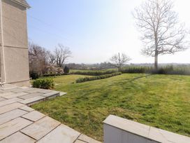 A garden with grass a tree and a stone patio at Hen Ficerdy in Abererch near Pwllheli