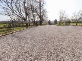 A gravel driveway bordered by grass and trees at Hen Ficerdy Abererch near Pwllheli