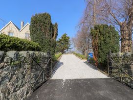 A gravel driveway lined with hedges and trees leading to a closed wooden gate at Hen Ficerdy in Abererch near Pwllheli