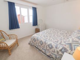 A bedroom with a bed and a chair at Flat 2, Moonrakers in St. Ives