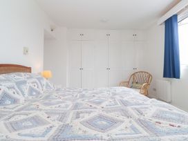 A bedroom with a bed, lamp, wardrobe, chair, and curtain at Flat 2, Moonrakers St. Ives