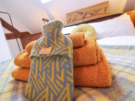A stack of towels and a hand warmer on a bed at The Granary in Welshpool
