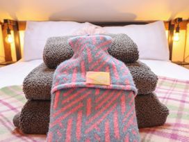 Towels and a hot water bottle on a bed at The Granary in Welshpool