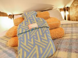 A hot water bottle and stacked towels on a bed at The Granary in Welshpool