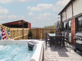 An outdoor area featuring a hot tub, dining table, chairs, and barbecue grill at The Granary Llangyniew near Llanfair Caereinion