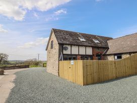 A building with a gravel driveway and wooden fence at The Granary in Llangyniew near Llanfair Caereinion