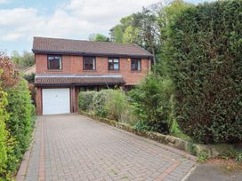A two-story brick house with a tiled roof garage and a paved driveway surrounded by bushes at Sparrow House in Alnwick