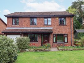 A two story brick house with a tiled roof and a front garden with flowers and bushes at Sparrow House in Alnwick