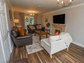 A living room with brown leather sofas a beige armchair a wooden coffee table a TV mounted above a fireplace and wood flooring at Sparrow House in Alnwick