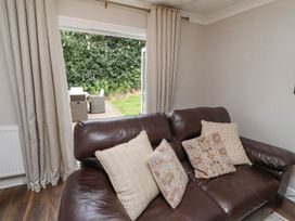 A brown leather sofa with four cushions in a living room with open curtains showing an outdoor patio at Sparrow House in Alnwick
