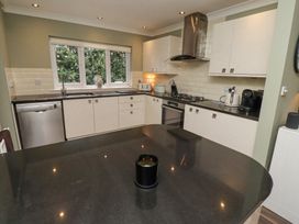 A kitchen with black countertops white cabinets a window and various appliances at Sparrow House in Alnwick
