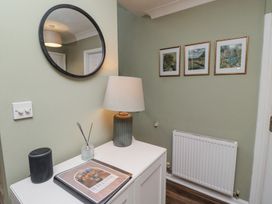 A hallway with a round mirror a table lamp a small cabinet and three framed pictures above a radiator at Sparrow House in Alnwick