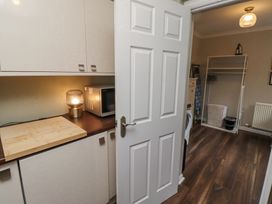 A utility room with a microwave lamp and cutting board on the counter a washing machine laundry basket and ironing board at Sparrow House in Alnwick