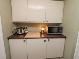 A kitchen countertop with a slow cooker microwave wooden cutting board and a lamp at Sparrow House in Alnwick