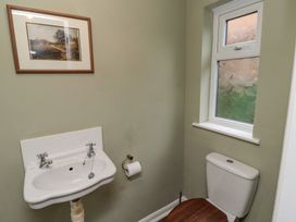 A bathroom with a white sink and toilet with wooden toilet seat under a window at Sparrow House in Alnwick