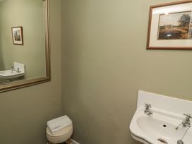 A bathroom with a white sink a round stool with folded towels a large mirror and framed pictures on the wall at Sparrow House in Alnwick