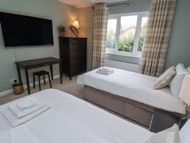 A bedroom with two single beds a desk a chest of drawers and a wall mounted television at Sparrow House in Alnwick