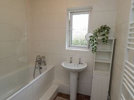 A bathroom with a bathtub a pedestal sink a shelving unit with a plant and a frosted window at Sparrow House in Alnwick