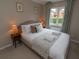 A bedroom with a bed with pillows and folded towels next to a window with curtains at Sparrow House in Alnwick
