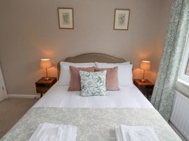 A bedroom with a double bed two side tables with lamps two framed pictures on the wall and patterned curtains at Sparrow House in Alnwick