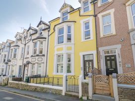 A row of terraced houses with black doors and windows including a yellow house at DownTown - Manhattan House in Llandudno