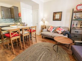 A kitchen and living area with wooden chairs and a round table at DownTown Manhattan House in Llandudno