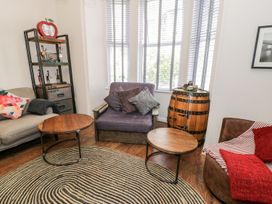 A living room with various chairs wooden tables a barrel side table and a shelving unit at DownTown - Manhattan House in Llandudno