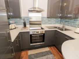 A kitchen with grey cabinets stainless steel oven and sink a toaster and kettle on the counter at DownTown - Manhattan House in Llandudno