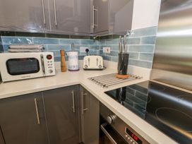 A kitchen corner with a microwave oven toaster paper towel holder knife block electric stove and oven at DownTown - Manhattan House in Llandudno