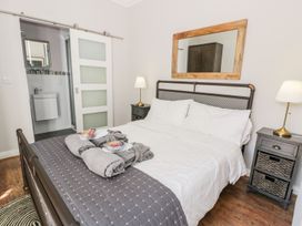 A bedroom with a bed white bedding gray blanket wooden floor and sliding door to a bathroom at DownTown - Manhattan House in Llandudno