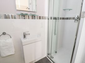 A bathroom with a small sink and a glass door shower at DownTown - Manhattan House in Llandudno